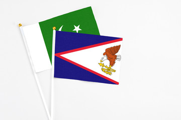 American Samoa and Pakistan stick flags on white background. High quality fabric, miniature national flag. Peaceful global concept.White floor for copy space.