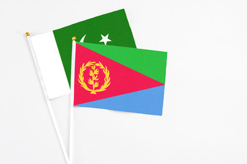 Eritrea and Pakistan stick flags on white background. High quality fabric, miniature national flag. Peaceful global concept.White floor for copy space.