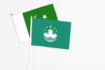 Macao and Pakistan stick flags on white background. High quality fabric, miniature national flag. Peaceful global concept.White floor for copy space.