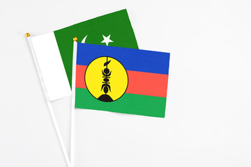 New Caledonia and Pakistan stick flags on white background. High quality fabric, miniature national flag. Peaceful global concept.White floor for copy space.