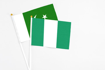 Nigeria and Pakistan stick flags on white background. High quality fabric, miniature national flag. Peaceful global concept.White floor for copy space.