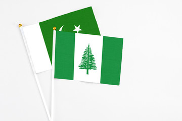 Norfolk Island and Pakistan stick flags on white background. High quality fabric, miniature national flag. Peaceful global concept.White floor for copy space.
