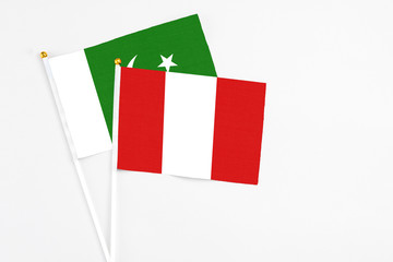 Peru and Pakistan stick flags on white background. High quality fabric, miniature national flag. Peaceful global concept.White floor for copy space.