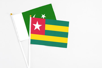 Togo and Pakistan stick flags on white background. High quality fabric, miniature national flag. Peaceful global concept.White floor for copy space.