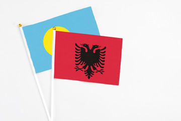 Albania and Palau stick flags on white background. High quality fabric, miniature national flag. Peaceful global concept.White floor for copy space.