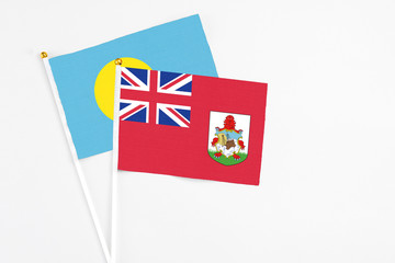 Bermuda and Palau stick flags on white background. High quality fabric, miniature national flag. Peaceful global concept.White floor for copy space.