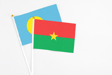 Burkina Faso and Palau stick flags on white background. High quality fabric, miniature national flag. Peaceful global concept.White floor for copy space.