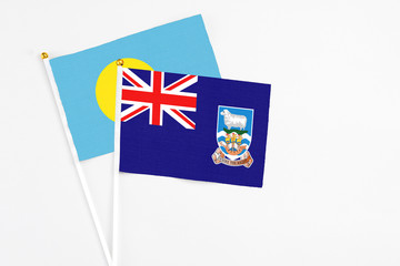 Falkland Islands and Palau stick flags on white background. High quality fabric, miniature national flag. Peaceful global concept.White floor for copy space.