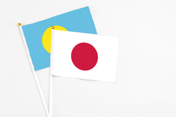 Japan and Palau stick flags on white background. High quality fabric, miniature national flag. Peaceful global concept.White floor for copy space.