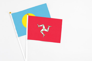 Isle Of Man and Palau stick flags on white background. High quality fabric, miniature national flag. Peaceful global concept.White floor for copy space.
