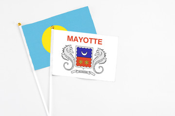 Mayotte and Palau stick flags on white background. High quality fabric, miniature national flag. Peaceful global concept.White floor for copy space.