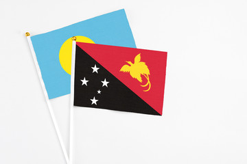 Papua New Guinea and Palau stick flags on white background. High quality fabric, miniature national flag. Peaceful global concept.White floor for copy space.