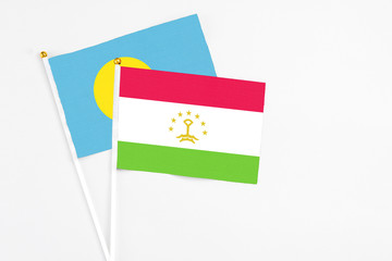 Tajikistan and Palau stick flags on white background. High quality fabric, miniature national flag. Peaceful global concept.White floor for copy space.