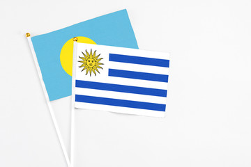 Uruguay and Palau stick flags on white background. High quality fabric, miniature national flag. Peaceful global concept.White floor for copy space.