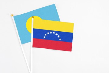 Venezuela and Palau stick flags on white background. High quality fabric, miniature national flag. Peaceful global concept.White floor for copy space.