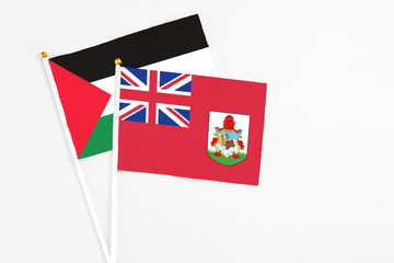 Fototapeta premium Bermuda and Palestine stick flags on white background. High quality fabric, miniature national flag. Peaceful global concept.White floor for copy space.