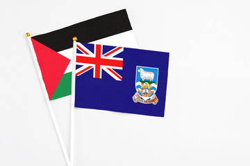 Fototapeta premium Falkland Islands and Palestine stick flags on white background. High quality fabric, miniature national flag. Peaceful global concept.White floor for copy space.