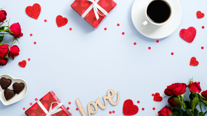 Valentine's day holiday card. Flat lay presents, red hearts shape, candy, coffee cup, rose flowers, text sign "Love" on blue background. Romantic frame border, greeting card mockup