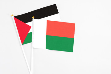 Madagascar and Palestine stick flags on white background. High quality fabric, miniature national flag. Peaceful global concept.White floor for copy space.