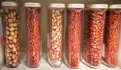 Capacity plastic vertical jars with peanuts hazelnuts pistachios on the shelf. Food, plants, agriculture, useful products.
