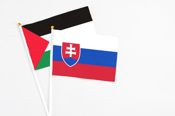 Slovakia and Palestine stick flags on white background. High quality fabric, miniature national flag. Peaceful global concept.White floor for copy space.