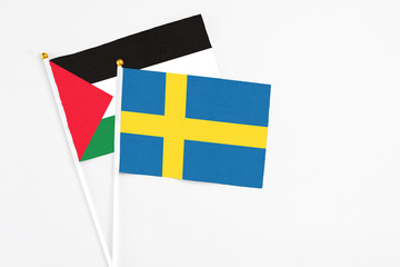 Sweden and Palestine stick flags on white background. High quality fabric, miniature national flag. Peaceful global concept.White floor for copy space.