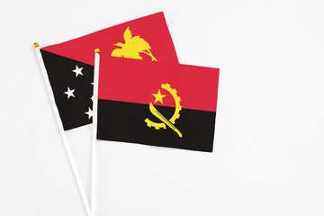 Angola and Papua New Guinea stick flags on white background. High quality fabric, miniature national flag. Peaceful global concept.White floor for copy space.