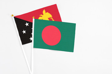 Bangladesh and Papua New Guinea stick flags on white background. High quality fabric, miniature national flag. Peaceful global concept.White floor for copy space.