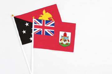 Bermuda and Papua New Guinea stick flags on white background. High quality fabric, miniature national flag. Peaceful global concept.White floor for copy space.