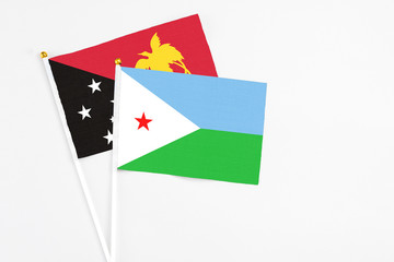 Djibouti and Papua New Guinea stick flags on white background. High quality fabric, miniature national flag. Peaceful global concept.White floor for copy space.