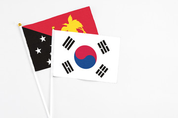 South Korea and Papua New Guinea stick flags on white background. High quality fabric, miniature national flag. Peaceful global concept.White floor for copy space.