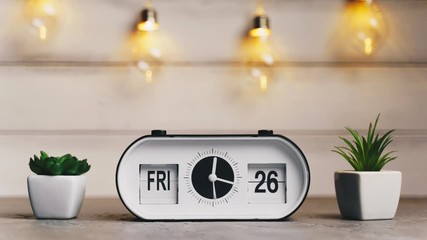 A white flip clock on table turns through month, flipping days and date, countdown from 1st to 31th