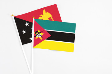 Mozambique and Papua New Guinea stick flags on white background. High quality fabric, miniature national flag. Peaceful global concept.White floor for copy space.