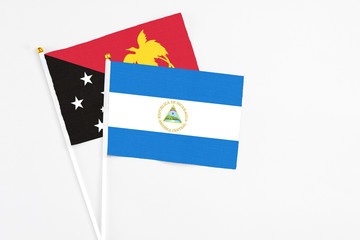 Nicaragua and Papua New Guinea stick flags on white background. High quality fabric, miniature national flag. Peaceful global concept.White floor for copy space.