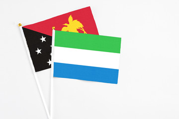 Sierra Leone and Papua New Guinea stick flags on white background. High quality fabric, miniature national flag. Peaceful global concept.White floor for copy space.