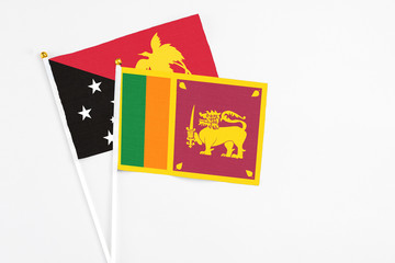 Sri Lanka and Papua New Guinea stick flags on white background. High quality fabric, miniature national flag. Peaceful global concept.White floor for copy space.