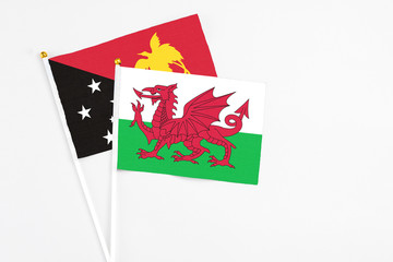 Wales and Papua New Guinea stick flags on white background. High quality fabric, miniature national flag. Peaceful global concept.White floor for copy space.