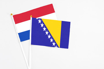 Bosnia Herzegovina and Paraguay stick flags on white background. High quality fabric, miniature national flag. Peaceful global concept.White floor for copy space.