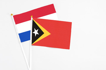 East Timor and Paraguay stick flags on white background. High quality fabric, miniature national flag. Peaceful global concept.White floor for copy space.
