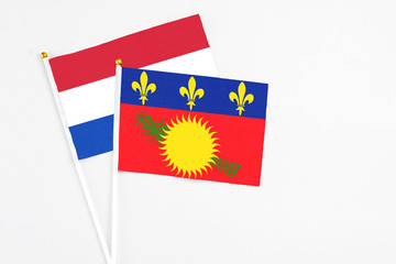 Fototapeta premium Guadeloupe and Paraguay stick flags on white background. High quality fabric, miniature national flag. Peaceful global concept.White floor for copy space.