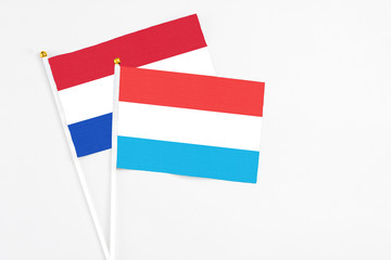 Luxembourg and Paraguay stick flags on white background. High quality fabric, miniature national flag. Peaceful global concept.White floor for copy space.