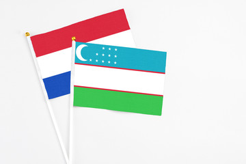 Uzbekistan and Paraguay stick flags on white background. High quality fabric, miniature national flag. Peaceful global concept.White floor for copy space.