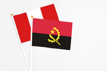 Angola and Peru stick flags on white background. High quality fabric, miniature national flag. Peaceful global concept.White floor for copy space.