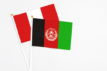 Afghanistan and Peru stick flags on white background. High quality fabric, miniature national flag. Peaceful global concept.White floor for copy space.