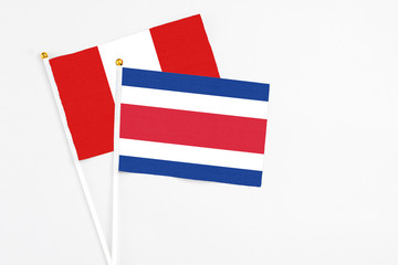 Costa Rica and Peru stick flags on white background. High quality fabric, miniature national flag. Peaceful global concept.White floor for copy space.