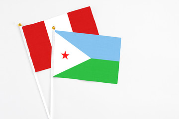 Djibouti and Peru stick flags on white background. High quality fabric, miniature national flag. Peaceful global concept.White floor for copy space.