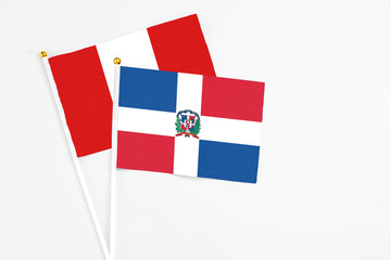 Dominican Republic and Peru stick flags on white background. High quality fabric, miniature national flag. Peaceful global concept.White floor for copy space.