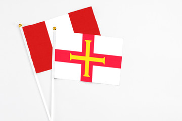 Guernsey and Peru stick flags on white background. High quality fabric, miniature national flag. Peaceful global concept.White floor for copy space.