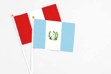 Guatemala and Peru stick flags on white background. High quality fabric, miniature national flag. Peaceful global concept.White floor for copy space.