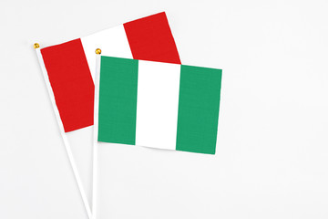 Nigeria and Peru stick flags on white background. High quality fabric, miniature national flag. Peaceful global concept.White floor for copy space.